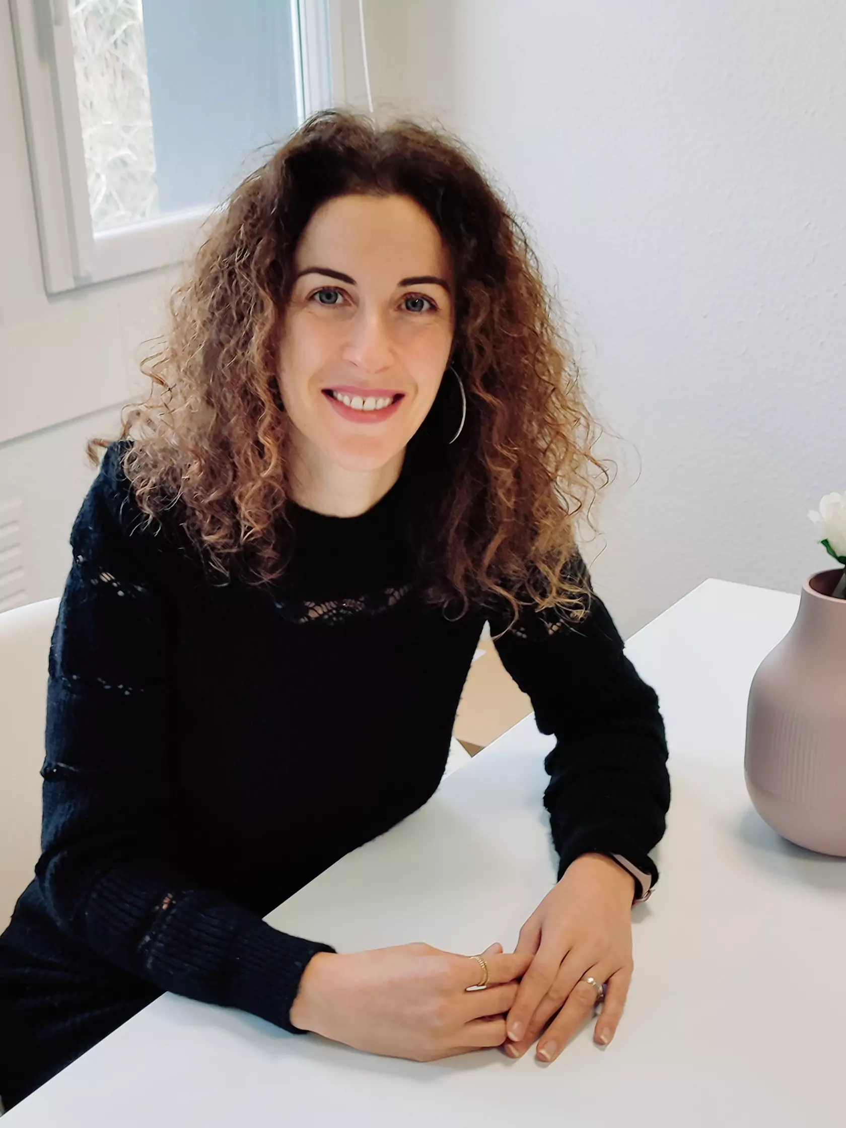 Aurélie assise à son bureau, travaillant devant un ordinateur, entourée d’un environnement professionnel moderne