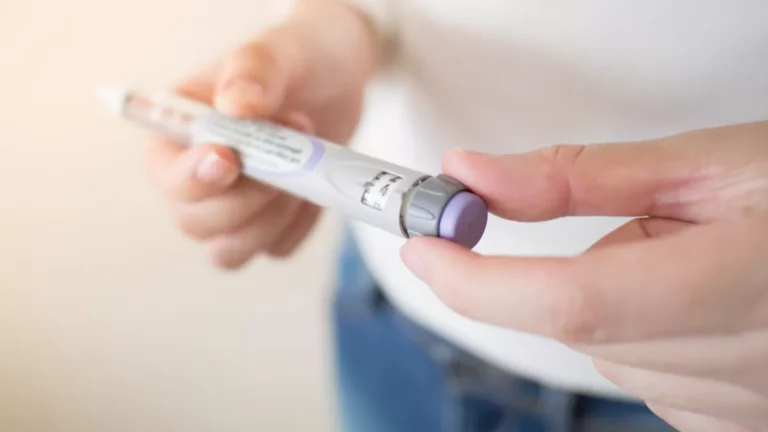 Gros plan sur les mains d’une personne réglant la dose d’un stylo injecteur.